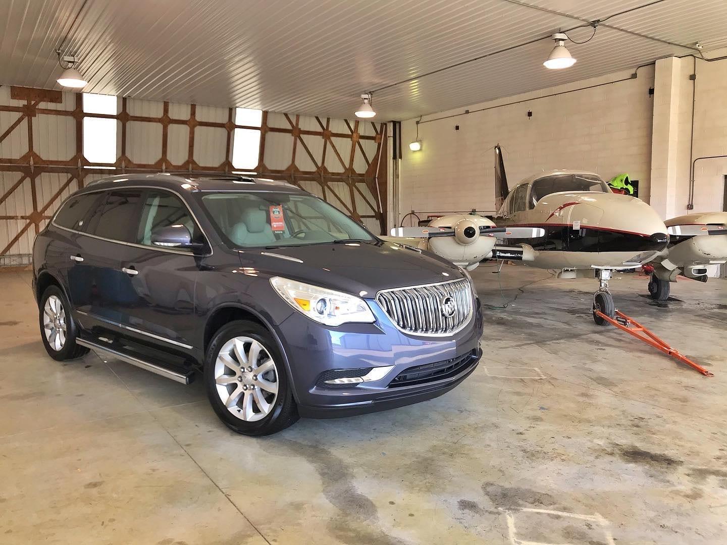 Detailed Buick SUV beside a twin-engine aircraft in a hangar